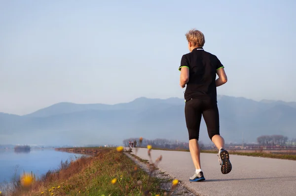 Young man jogging near lake — Stock Photo, Image