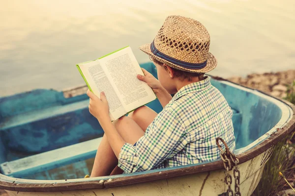 Lesen junge in altes Boot — Stockfoto