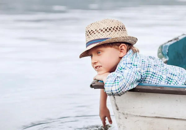 Pojken i stråhatt ligga i båten — Stockfoto