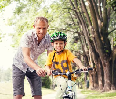 Father learn  son to ride bicykle