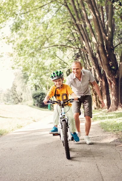 Padre aiutare suo figlio a cavalcare biciclette — Foto Stock