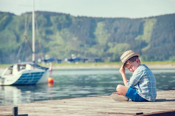 Pojken sitter på träpiren — Stockfoto