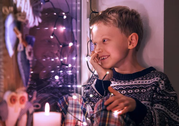 Ragazzo sulla finestra con luci di Natale — Foto Stock