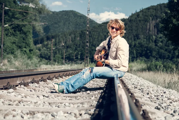 Oung homem com guitarra na Ferroviária — Fotografia de Stock