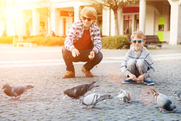 Мальчики, кормление голубей на городской площади — стоковое фото