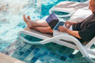Orta yaşlı serbest çalışan CEO işletme sahibi lüks otelin havuzunda dizüstü bilgisayarda çalışıyor. Dijital göçebe, uzak tropikal yaz tatili şirketini başarıyla yönetiyor..