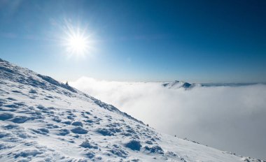 Maly Krivan dağın tepesi 1668 metre yükseklikte parlak güneş tarafından aydınlatılan bulutların üzerinde görülüyor. Velky Krivan 'ın Ocak sonu kış sezonu manzarası. Mala Fatra aralığı, Slovakya Cumhuriyeti seyahat turizmi manzarası