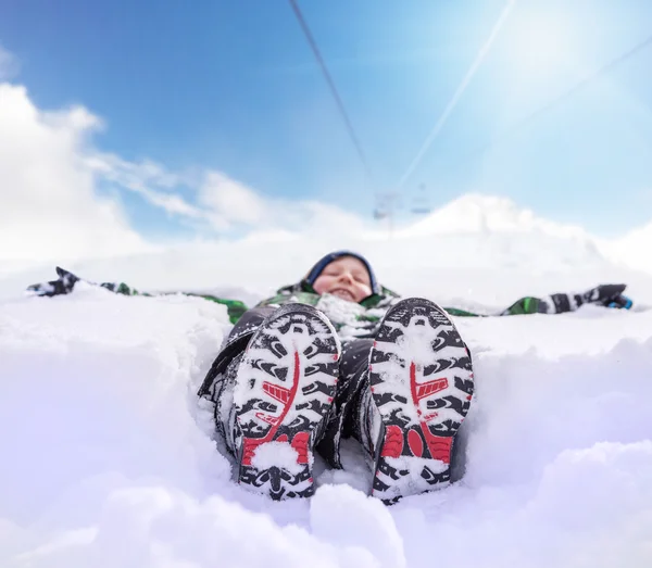 Мальчик, лежащий в глубоком снегу — стоковое фото