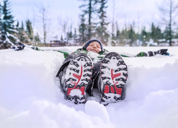 深い雪の中で横になっている男の子 — ストック写真