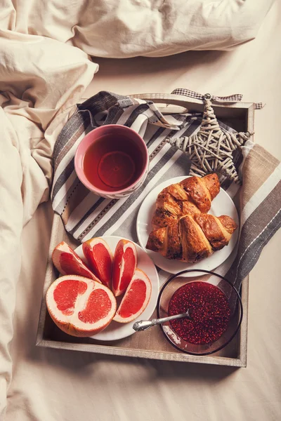 Kruvasan ve yatakta çay — Stok fotoğraf