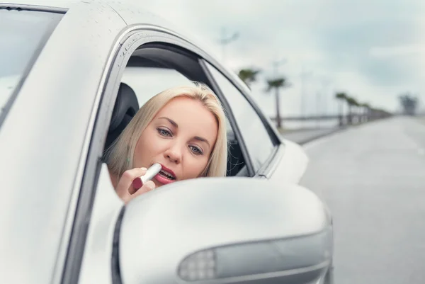 Mujer aplicar lápiz labial en el espejo de coche — Foto de Stock