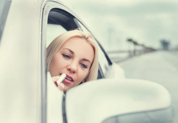 Femme appliquer le rouge à lèvres dans le miroir de voiture — Photo