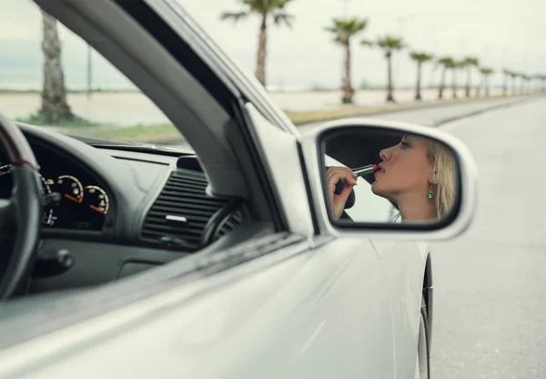 Mujer aplicando lápiz labial en el coche — Foto de Stock