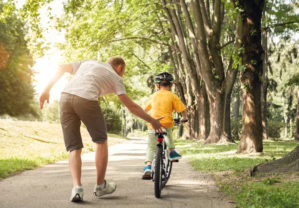 Отец учит сына, чтобы ездить на велосипеде — стоковое фото
