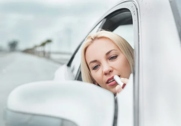 Woman apply lipstick in car — Stock Photo, Image