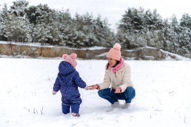 Karlı kış ülkesinde küçük çocuklu bir anne oynuyor.