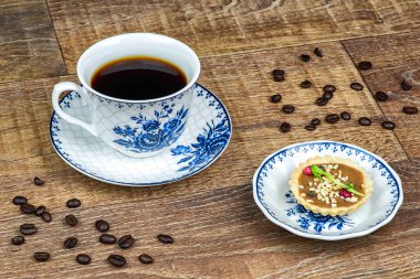 Tabakta bir fincan kahve ve tart. Kahve çekirdeği.