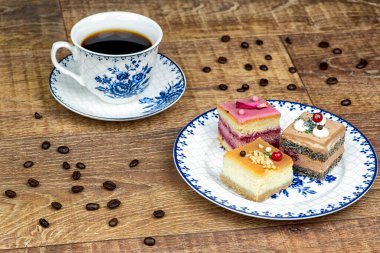 Tabakta bir fincan kahve ve kek. Beyaz arka planda kahve çekirdekleri.