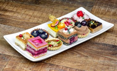 Masadaki beyaz tabakta çeşitli lezzetli meyveli kekler.