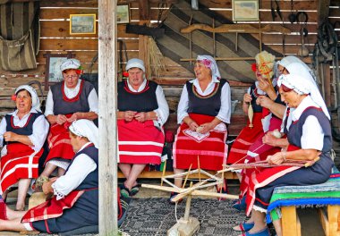 BRASHLYAN, BULGARIA - 16 Temmuz 2013: Halk kostümlü Bulgar yaşlı kadınlar evin dışında örgü örüyor