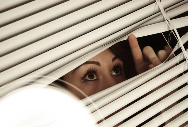Chica mirando a través de las persianas —  Fotos de Stock