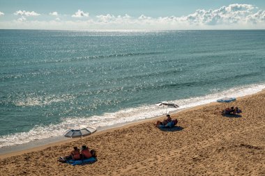 Bulgaristan 'ın Byala kenti - 21 Eylül 2025: İnsanlar Karadeniz kıyısındaki kumsalda şemsiyeler altında güneşleniyor. Sahil turizminin sıcak seyahat sahnesi.