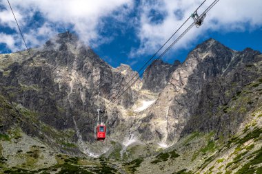 Tatranska Lomnica, Slovakya - 21 Haziran 2025: High Tatras dağlarındaki Lomnicky tepesine hareket eden kırmızı teleferiğe yakın çekim, turizm ve dağ macerasının sembolü.