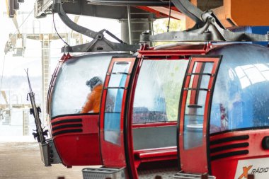 Ruzomberok, Slovakya - 4 Ocak 2025: Malino Brdo kayak sezonu boyunca teleferik istasyonunda bekleyen kırmızı gondollu kayakçı.