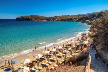 Girit, Yunanistan - 2 Eylül 2025: Yunanistan 'ın Girit kentindeki Voulisma Plajı' nda güneşli yaz günlerinde turkuaz deniz, güneşlik yataklar ve şemsiyelerle dinlenen turistler.