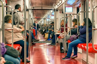 Milan, İtalya - 13 Nisan 2018: Milano metro treni içinde seyahat eden yolcular, her gün gidip gelirken, iç hatları ve koltukları parlak modern metro sürücülerini göstermektedir..