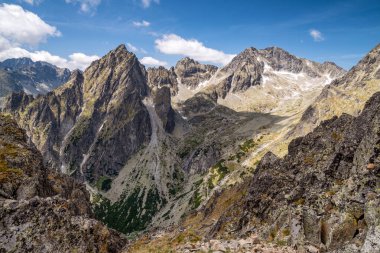 Slovakya 'da açık bir yaz gününde, Mala Öğrenci Dolina Vadisi' nin panoramik manzarası ve Lomnicke sedlo 'dan görülen engebeli yüksek Tatras tepeleri dramatik alp manzarasını gösteriyor..