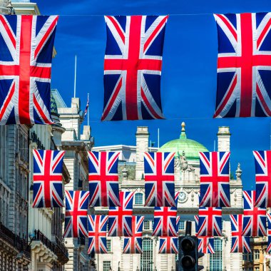 Büyük Britanya 'nın bayrakları, güneşli bir günde Londra' nın merkezindeki bir caddenin üzerinde sallanıyor. Bayram havası yaratıyor ve ulusal kimliği ve İngiliz kültürünü sembolize ediyor..