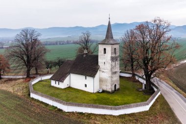 Slovakya 'nın Ludrova kentindeki tarihi kilise kulesi ve savunma duvarının insansız hava aracı görüntüsü, sonbahar renklerine sahip kırsal Liptov arazisinde, miras, mimarlık ve seyahat temaları için ideal..