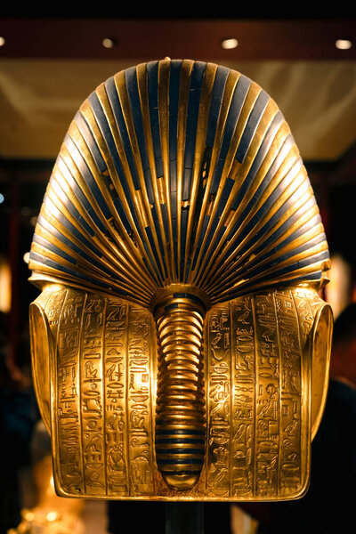 Close-up view of Tutankhamun golden funerary mask, showing detailed hieroglyphs, royal craftsmanship and cultural symbolism of ancient Egyptian burial art.
