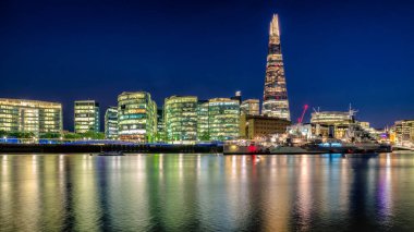 Londra, Birleşik Krallık - 14 Mayıs 2018: Londra 'nın gökdelenli gece manzarası ve Thames Nehri' ne yansıyan HMS Belfast.
