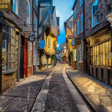 York, İngiltere - 15 Mayıs 2018: Ortaçağ kereste çerçeveli evleri ve York şehrinde mavi saatte aydınlatılan küçük dükkanları olan Shambles tarihi caddesi.