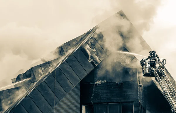 Bombeiro e telhado queimado — Fotografia de Stock