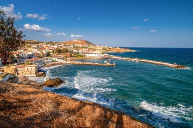 Yunanistan 'ın Girit adasında açık mavi gökyüzü ile güneşli bir günde yakalanan küçük bir liman ve turkuaz Akdeniz dalgalarıyla Panormos sahil balıkçı köyünün resimli panoramik manzarası.