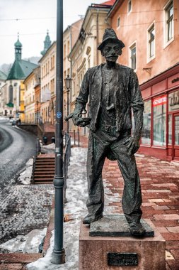 Banska Stiavnica, Slovakya - 31 Ocak 2026: Stiavnicky Nacko heykeli, yerel bir kasaba karakteri, arka planda renkli binalarla tarihi eski kasaba caddesinde duruyor.
