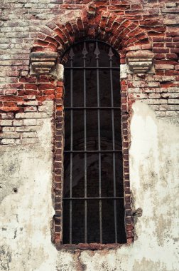 Fragment of a brick wall with a window with a lattice of a medieval church as texture or background