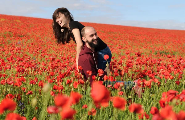 Junge Männer und Frauen beim Date im Mohnfeld Stockbild