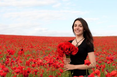 Bir buket kırmızı haşhaş olan mutlu kadın