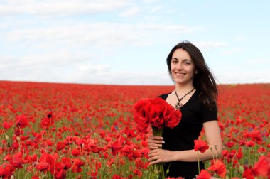 Bir buket kırmızı haşhaş olan mutlu kadın