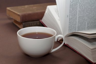 Fincan siyah çay ve kahverengi surfa yalan okumak için bazı kitaplar