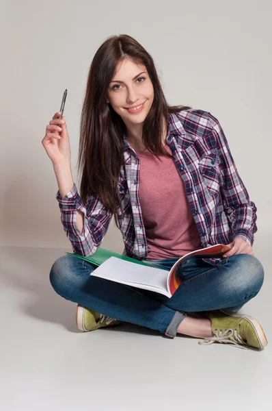 Junge Frau (Teenager-Mädchen) beim Lesen von Büchern. grauer Hintergrund — Stockfoto