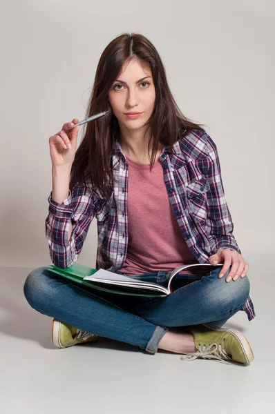 Young woman (teen girl) reading book. Grey background — Stock Photo, Image