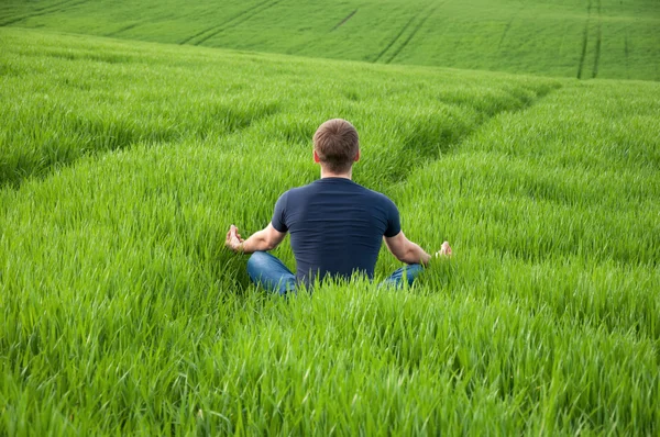 L'homme est assis au milieu d'une prairie verte — Photo