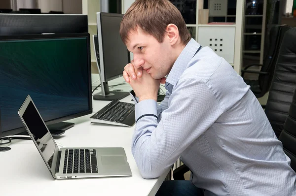 Young handsome man with computer in the office. Thinking over ta — Stock Photo, Image