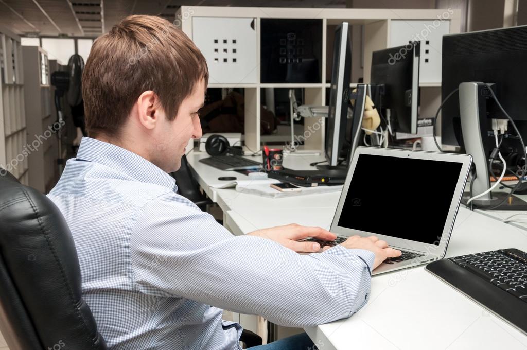 Young handsome man with computer in the office. Thinking over task in programming