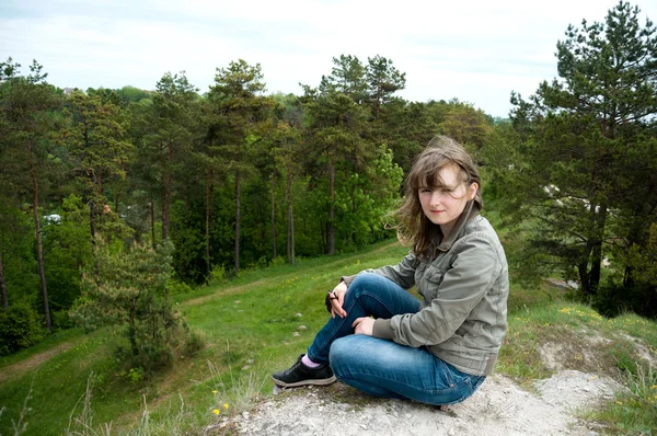 Ung flicka sitter på en kulle i skogen. Meditation — Stockfoto